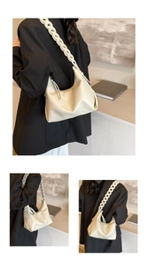 Detail of minimalist beige leather underarm bag featuring a textured ring chain strap
