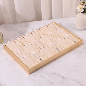 Detail view of beige velvet jewelry tray for necklaces with metal frame on marble desk