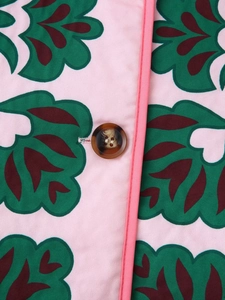 Macro detail of amber button and pink floral patterned woven fabric on fashion jacket