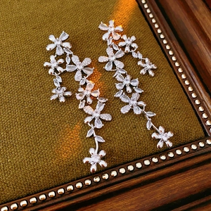 Close-up of sparkling flower tassel earrings with zircons on a green velvet jewelry box