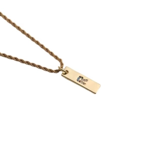Macro view of gold rectangle pendant necklace with colorful zircon letter inlay