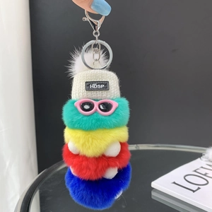 Detail of colorful plush caterpillar keychain with pink glasses and white knit cap