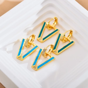 Macro detail of V-shaped gold earrings with colorful enamel and sparkling crystal stones