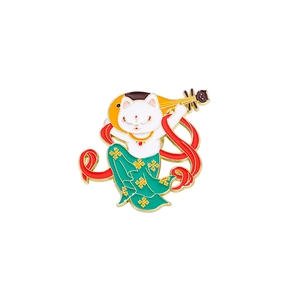 Detail of enamel cat badge playing pipa with golden trim and traditional red ribbons