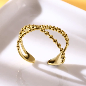 Close-up of golden stainless steel double-row bead ring on white minimalist display stand