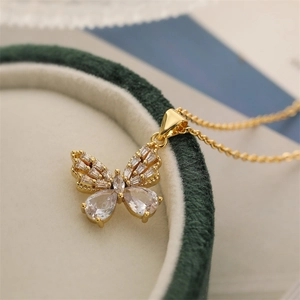 Detail of a gold butterfly pendant with zircons resting on a green velvet jewelry box