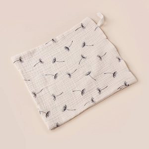 Detail view of a cream cotton muslin baby washcloth with dandelion print and loop