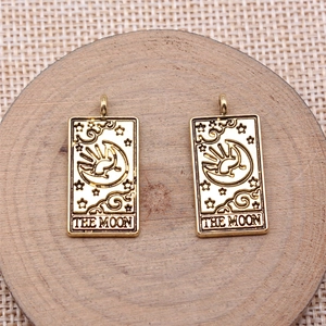 Macro shot of two vintage golden Tarot Moon pendants on a wooden pedestal with woven texture