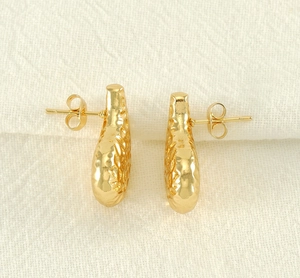 Vue détaillée de boucles d'oreilles dorées en goutte avec finition en métal martelé