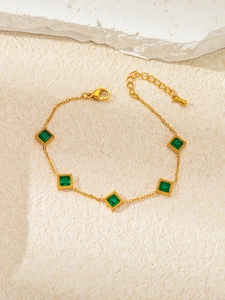 Detail view of gold star bracelet featuring green emerald zircons and lobster clasp closure