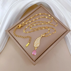 Detailed macro view of gold-plated stainless steel angel wing necklace with pink gemstone