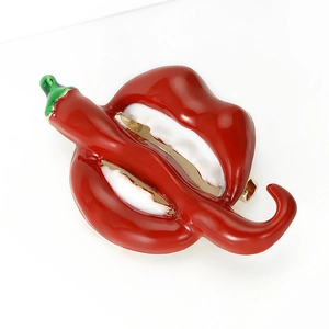 Detailed view of red enamel lip and chili brooch with polished metallic texture