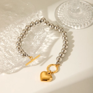 Detailed shot of silver beaded bracelet with gold heart pendant and OT clasp
