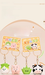 Detail of four resin keychains featuring cute pig, cabbage, cow, and clover characters