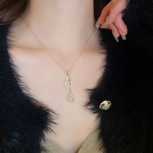Détail du collier pendentif double gourde en or rose serti de zircons sur manteau noir