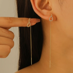 Macro detail of gold tassel drop earrings with shimmering micro-paved waterdrop charms