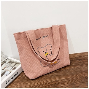 Close-up of pink corduroy tote bag featuring a cute cartoon bear embroidery on wood surface
