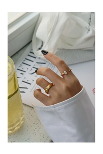 Detailed view of gold textured rings with white opal gemstone on hand with magazine