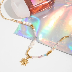 Detail of colorful beads and freshwater pearls necklace with golden sun pendant charm