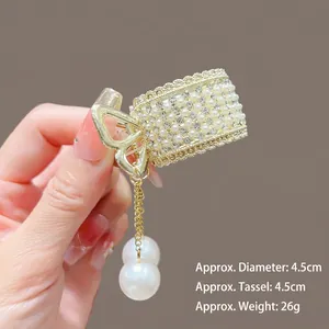 Détail d'une pince à cheveux lotus dorée avec perles, strass et pompon, 4,5 cm de diamètre