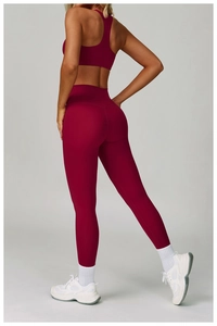 Dettaglio del reggiseno sportivo con vogatore e leggings a vita alta in tessuto rosso scuro