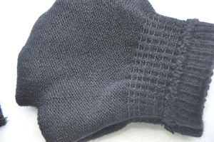 Macro detail of elastic ribbed cuffs on black knitted skull fingerless gloves