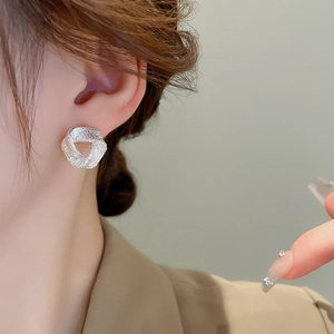 Close-up of silver geometric earrings with hammered texture on a female model