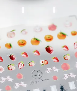 Dettaglio di adesivi per unghie con frutta e fiocchi rosa con texture opaca