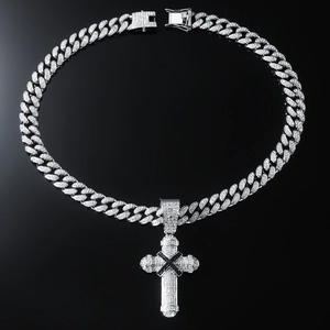 Macro detail of iced-out silver cross pendant with black X design on cuban link chain