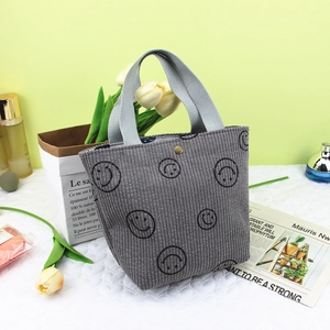 Détail du sac à main en velours côtelé gris avec motifs sourires et bouton pression