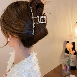 Elegant large metal hair claw with white pearls and green enamel on model's hairstyle