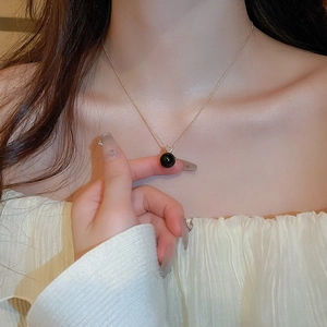 Detailed close-up of a black pearl pendant necklace with sparkling zircon on a gold chain