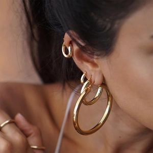 Polished 18K gold stainless steel hoop earrings set shown in various sizes on a model