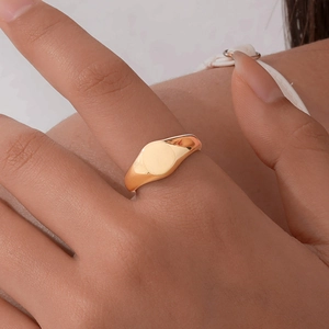 Close-up of a minimalist gold polished stainless steel signet ring on a model's finger