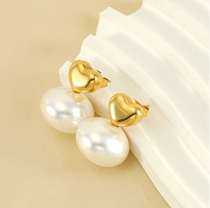 Detail of vintage heart stud earrings with large white pearls and gold-plated finish
