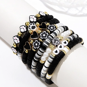 Detail of stacked bohemian beaded bracelets with clay hearts and flower patterns