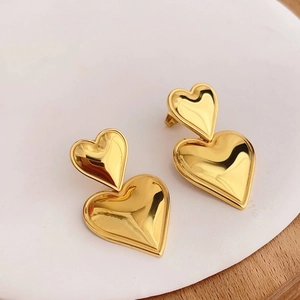 Close-up of golden double heart-shaped earrings on a white and wood display tray