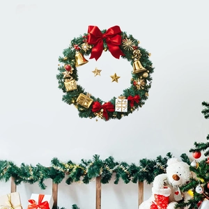 Christmas wreath with red bow, gold bells and stars on white wall background