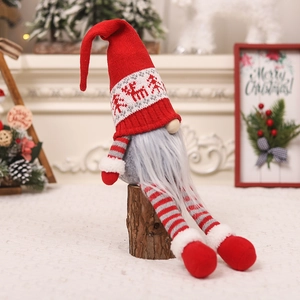 Christmas gnome doll with red knitted hat sitting on wooden log for holiday decoration
