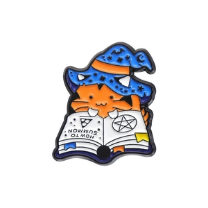 Detail of cartoon orange cat with blue wizard hat reading an enamel magic book pin