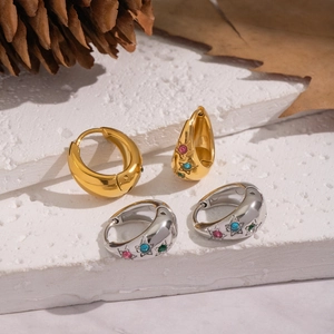 Detailed macro view of U-shaped gold and silver earrings with colorful zircon stars
