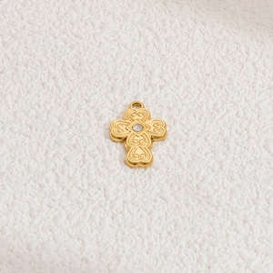 Detail of a golden cross pendant with heart engraving and a sparkling zircon center