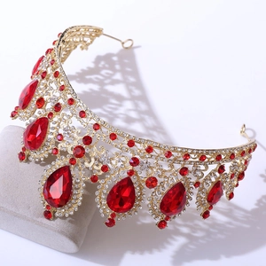 Close-up of golden crown with teardrop red gems and sparkling rhinestones