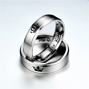 Detail of stainless steel couple rings with engraved crown and Her King His Queen text
