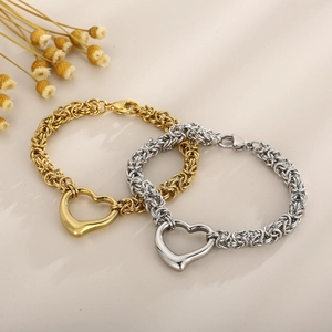 Detailed view of woven chain bracelets in gold and silver finish with heart pendants
