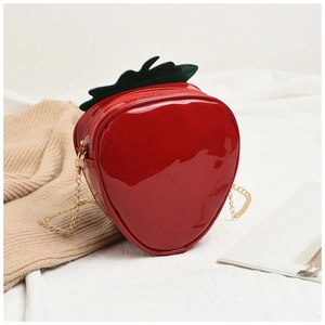 Macro shot of red strawberry crossbody bag with green leaf detail and gold chain strap