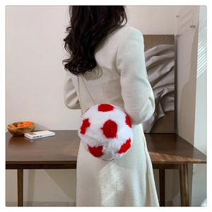 Detail of round plush crossbody bag with red polka dots and a golden metal chain