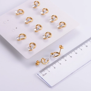Detail of twisted gold stud earrings with cubic zirconia stones showing size measurement