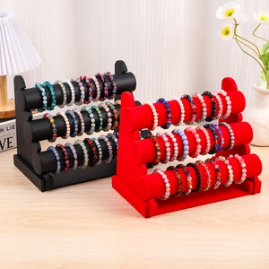 Three-tier jewelry display stand with black leather and red velvet tiers on a desk