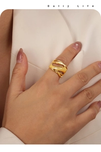 Detail of a gold layered wavy geometric ring worn by a model in formal business attire